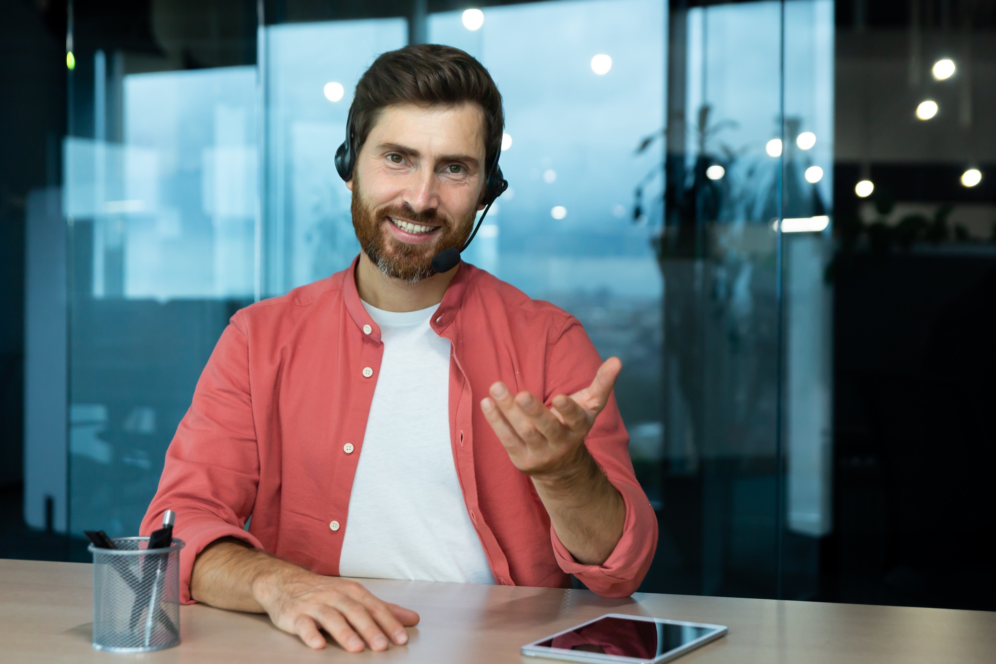 Webcam pov view, man in office with headset for video call smiling and looking into camera